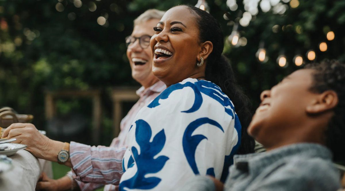 Friends laughing at an outdoor dinner gathering